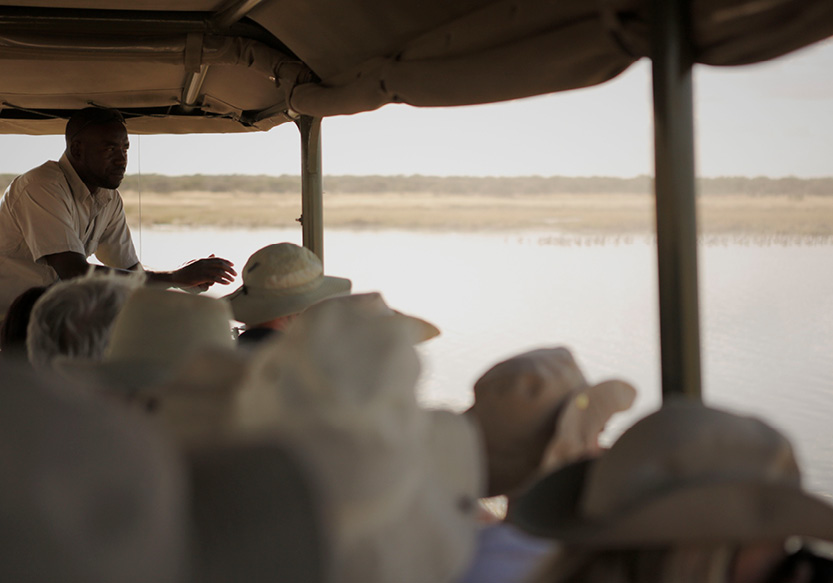 Mokuti Safari Tag Blick aus einem Safari-Fahrzeug mit einem Safari-Guide am Erzählen